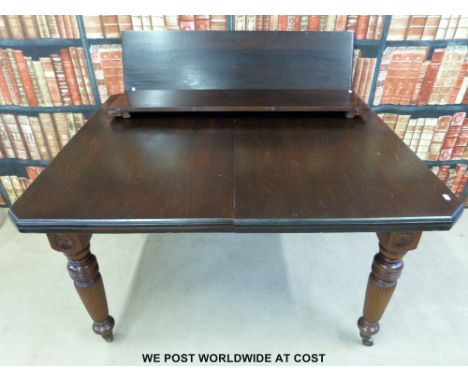 A mahogany extending dining table with two additional leaves and a winder, raised on turned and fluted legs terminating in ce