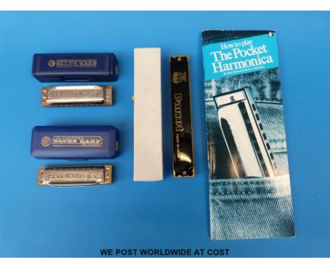 Two Hohner Blues harp harmonicas in unused condition, and a 24- hole Parrot Tremolo example with a pocket "How to Play" book