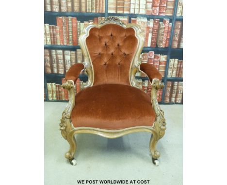 A 19thC carved walnut upholstered armchair raised on ceramic castors