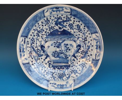 A 19thC Chinese blue and white charger, the central scene depicting two figures either side of a jar with Kangxi mark to base